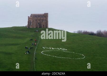 Abbotsbury, Dorset, Royaume-Uni. 22 novembre 2020. Météo au Royaume-Uni : l’événement caritatif annuel bougies sur la colline à la chapelle St Catheine’s Chapel à Abbotsbury, dans le Dorset, se poursuit au crépuscule avec le NHS écrit dans des lumières au-dessus du cercle de lumière sur le chemin menant à la chapelle pendant le confinement de Covid-19, lors d’une soirée de drizzly. Crédit photo : Graham Hunt/Alamy Live News Banque D'Images