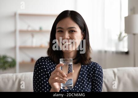 Portrait de tête souriant femme asiatique tenant un verre d'eau Banque D'Images