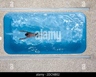 Le garçon nage dans la piscine. L'athlète s'entraîne en contre-courant. Centre de bien-être. Vue aérienne. Banque D'Images