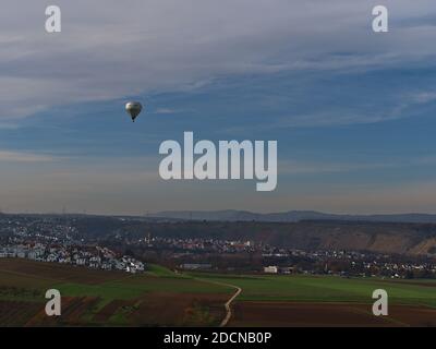 Ballon d'air chaud volant à basse altitude au-dessus des champs agricoles près du village Besigheim avec la vallée de la rivière Neckar et des vignobles en terrasse en arrière-plan. Banque D'Images