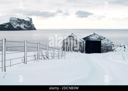 Deux hangars en bois en scène d'hiver avec des falaises dans le Arrière-plan sur les îles Orcades Banque D'Images