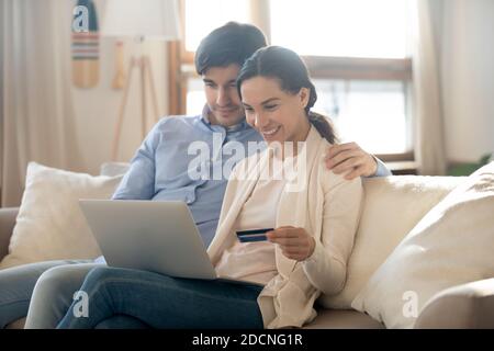 Heureux couple de la famille millénaire faisant le paiement en ligne à l'aide du service e-banking Banque D'Images