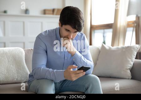 Homme inquiet regardant l'écran du téléphone en attente de nouvelles importantes Banque D'Images