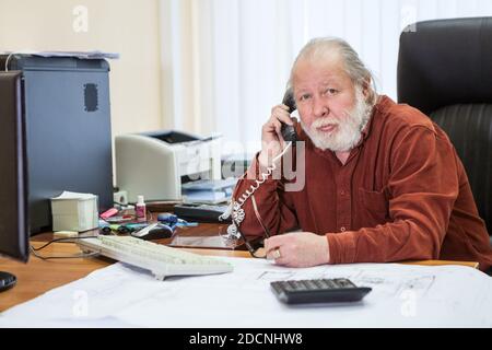 Portrait d'un homme d'affaires à barbe blanche utilisant le téléphone, appelant quelqu'un tout en travaillant dans la salle de bureau Banque D'Images