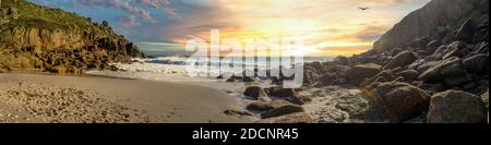 Vue sur une plage de Cornwall au coucher du soleil, avec les vagues s'écrasant sur les rochers. Porthgwarra Beach, tourné en novembre. Banque D'Images