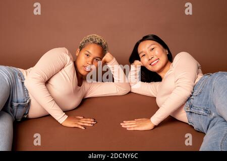 Deux jeunes femmes contemporaines de diverses origines ethniques en jeans et pull-overs Banque D'Images