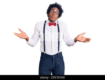 Beau afro-américain homme avec les cheveux afro porter hipster élégant look sans indice et expression confuse avec les bras et les mains soulevées. Doute concept. Banque D'Images
