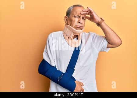 Beau mature homme âgé portant col et bras cervicaux sur le harnais inquiet et stressé au sujet d'un problème de main sur le front, nerveux et anxieux FO Banque D'Images