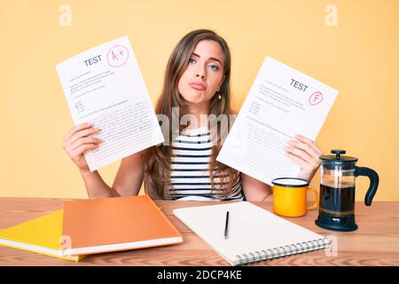 Jeune belle femme caucasienne montrant échoué et réussi examen assis sur la table déprimé et s'inquiéter de la détresse, pleurant en colère et peur. Triste exp Banque D'Images