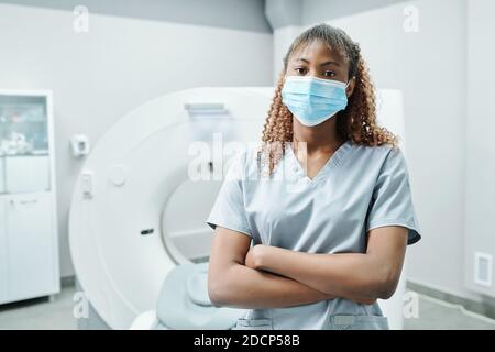 Jeune infirmière africaine ou médecin en masque de protection et uniforme bras croisés Banque D'Images