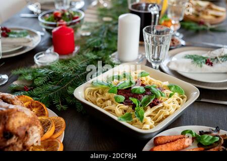 Table festive servie avec des pâtes, de la dinde rôtie, des assiettes, des bougies et d'autres Banque D'Images