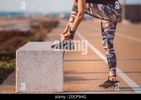 Gros plan sur une femme sportive de race blanche qui noue des lacets de chaussures. Préparation d'une séquence Banque D'Images