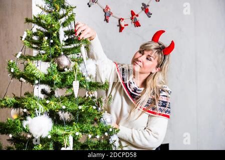 Femme blonde avec des cornes dévorant noël arbre Banque D'Images