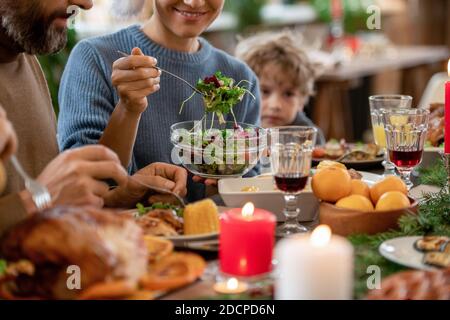 Jeune femme souriante mettant la salade de légumes du bol sur l'assiette de son mari Banque D'Images