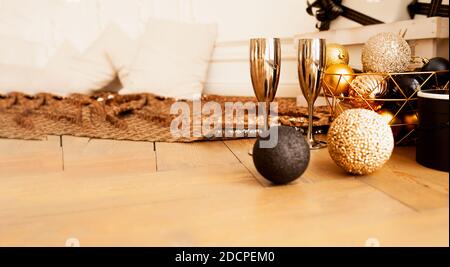 Banderole de Noël, deux verres à boire en métal doré sur parquet avec des décorations dans des tons or et noir: Balles rondes brillantes, boîtes-cadeaux, briller Banque D'Images