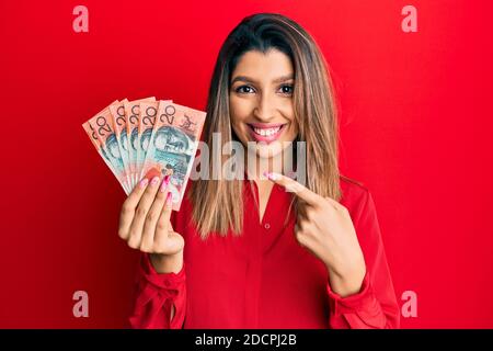 Belle brune femme tenant australien 20 dollars souriant heureux pointage avec la main et le doigt Banque D'Images