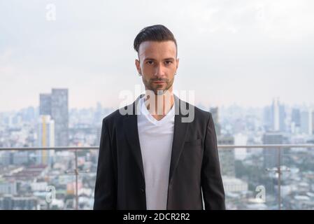 Portrait d'homme d'affaires debout sur le toit d'un gratte-ciel Banque D'Images