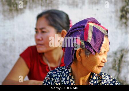 Deux laotiennes, une jeune et une plus âgée, dans la rue de Luang Prabang, au Laos. De deux générations différentes, ils regardent dans des directions opposées. Banque D'Images