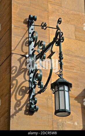 Une lumière victorienne en fer forgé ornée attachée à un mur en grès. Banque D'Images