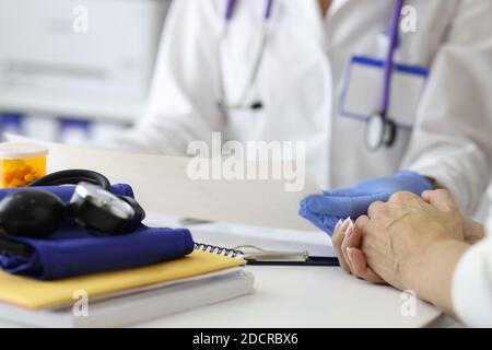 Médecin tenant le cardiogramme dans les mains et conseillant le patient en clinique Banque D'Images
