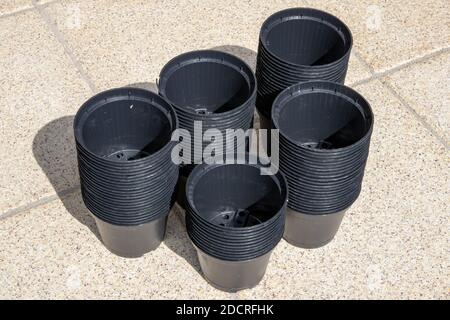 Gros plan des pots vides en plastique noir empilés sur la terrasse par temps ensoleillé. Équipement du jardinier pour la plantation de semis. Banque D'Images