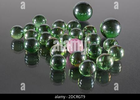 Petites boules de verre vert émeraude avec réflexion et une boule rose. Banque D'Images