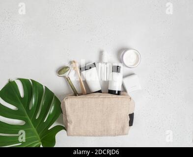 Sac cosmétique de voyage avec les moyens nécessaires pour prendre soin de la peau des femmes. Cosmétiques, masseur avec cristaux, shampooing sec, boutons en coton, brosses à dents en a Banque D'Images