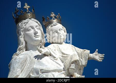 Détail d'une élégante sculpture de la Vierge Marie et du bébé Jésus en stuc blanc, vue sur le toit d'une église sur Ecija (Andalousie, Espagne) Banque D'Images