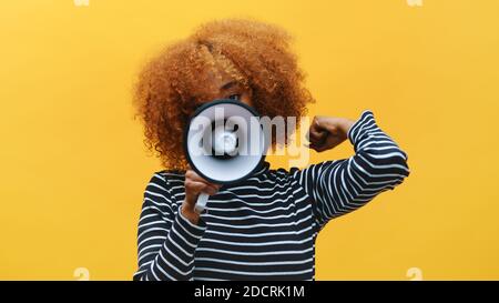 Femme noire afro-américaine aux cheveux bouclés criant dans le haut-parleur. Photo de haute qualité Banque D'Images