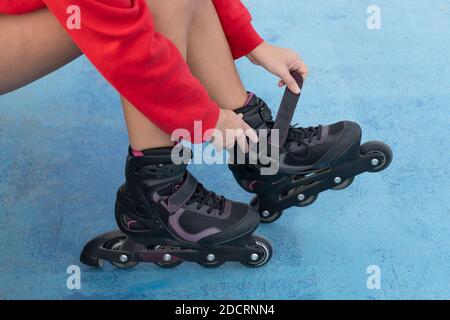 Femme assise nouant les lacets de patins à roulettes avant le patinage à roulettes.Sport active style de vie concept de fond. Banque D'Images