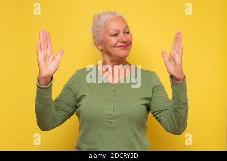 Une femme âgée souriante fait des mains de la taille d'une grande chose. Banque D'Images