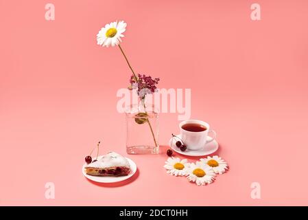 morceau de tarte aux cerises sur une assiette avec thé dans une tasse blanche. fond rose Banque D'Images