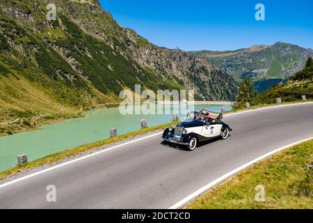 Une voiture d'époque Mercedes-Benz 170 V Cabrio passant devant un lac sur Silvretta Hochalpenstrasse pendant le rallye de voitures Arlberg Classic. Banque D'Images