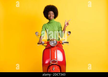 Photo portrait d'une fille afro-américaine brunette sur le pointage de moto isolé d'un doigt à l'autre sur un arrière-plan jaune vif Banque D'Images