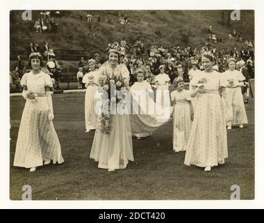 Photographie de presse du milieu du siècle d'une grande foule regardant la procession de la Reine de la Rose nouvellement couronnée et de ses accompagnateurs, qui tiennent le train de sa robe, lors d'une traditionnelle « Journée de marche », à Eagley, Bolton, Lancashire, nord-ouest de l'Angleterre,Royaume-Uni vers les années 1940 Banque D'Images