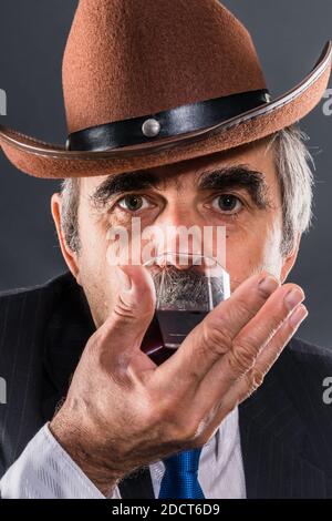 Homme âgé en costume avec cravate et chapeau de cowboy dégustation vin Banque D'Images