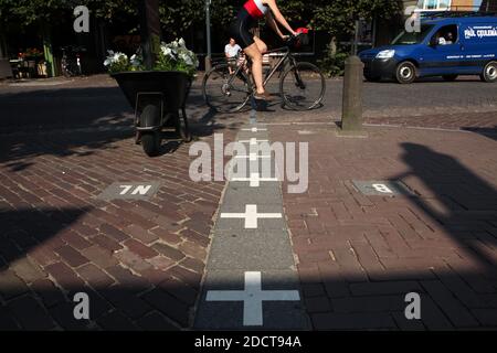 Le cycliste traverse la frontière compliquée entre la Belgique et les pays-Bas dans la ville de Baarle-Nassau aux pays-Bas. L'enclave belge est entourée par le territoire néerlandais. La partie belge de la ville est connue sous le nom de Baarle-Hertog. Banque D'Images