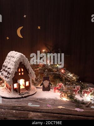 Belle maison de pain d'épice maison pour Noël et le nouvel an, fond sombre. Scène de Noël avec des ders, des lumières de Noël et un ciel étoilé. Banque D'Images