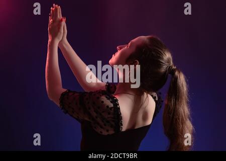 Portrait d'une belle jeune fille avec les mains soulevées à le ciel en couleur rétro-éclairage Banque D'Images
