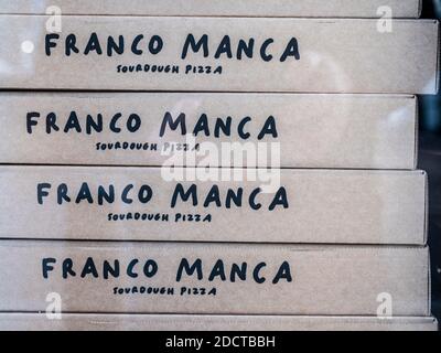 Boîtes à pizza en carton empilées dans une fenêtre d'un Franco Restaurant de pizza Manca Sourdough Banque D'Images