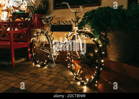 Décoration de Noël traditionnelle dans une rue nocturne de Zelenogradsk. Vélo d'époque décoré de lumières. Banque D'Images