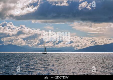 Magnifique paysage marin avec yacht, montagnes en arrière-plan et ciel bleu avec des nuages blancs Banque D'Images