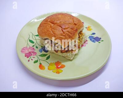 Le Dabeli est un en-cas indien servi avec des graines de grenade et du Cilantro dans une assiette en céramique blanche. C'est une cuisine populaire du Navratri Festival Banque D'Images