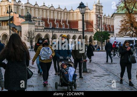 Les personnes portant des masques protecteurs contre la propagation du covid 19, alors qu'elles marchent sur la place principale inscrite au patrimoine mondial de l'UNESCO à Cracovie. Banque D'Images