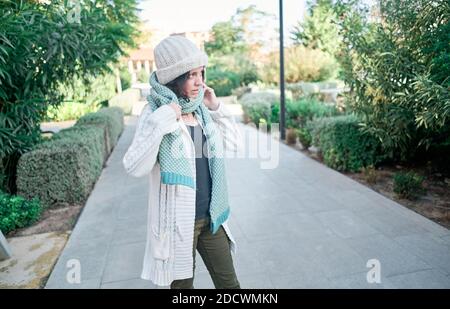 Un portrait d'une jolie jeune femme avec un chapeau blanc et une écharpe dans un parc. Automne, froid concept Banque D'Images