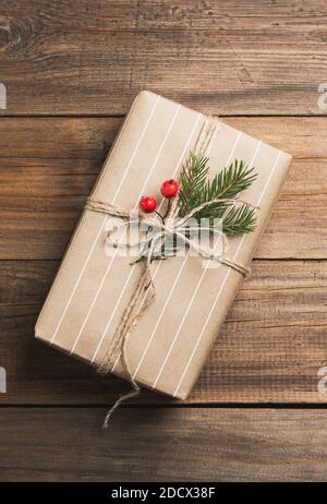 Boîte cadeau de Noël faite à la main dans un emballage en papier sur une sombre arrière-plan en bois Banque D'Images