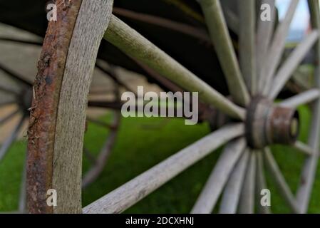 Ancienne roue de chariot en bois avec jante en métal rouillé, montée sur un chariot à cheval. Banque D'Images