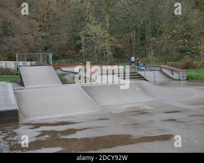 Parc de skate vide dans des rampes et des chemins en béton gris d'hiver les clôtures franchis les murs et les arbres en arrière-plan Banque D'Images