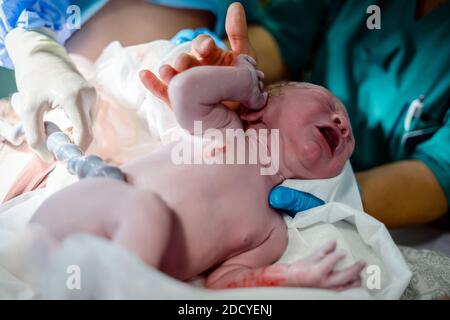 Nouveau-né bébé garçon toujours avec le cordon ombilical le reliant à mère Banque D'Images