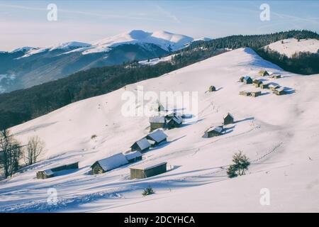 Paysage d'hiver dans une vallée de montagne avec des huttes. Huttes alpines traditionnelles recouvertes de neige Banque D'Images